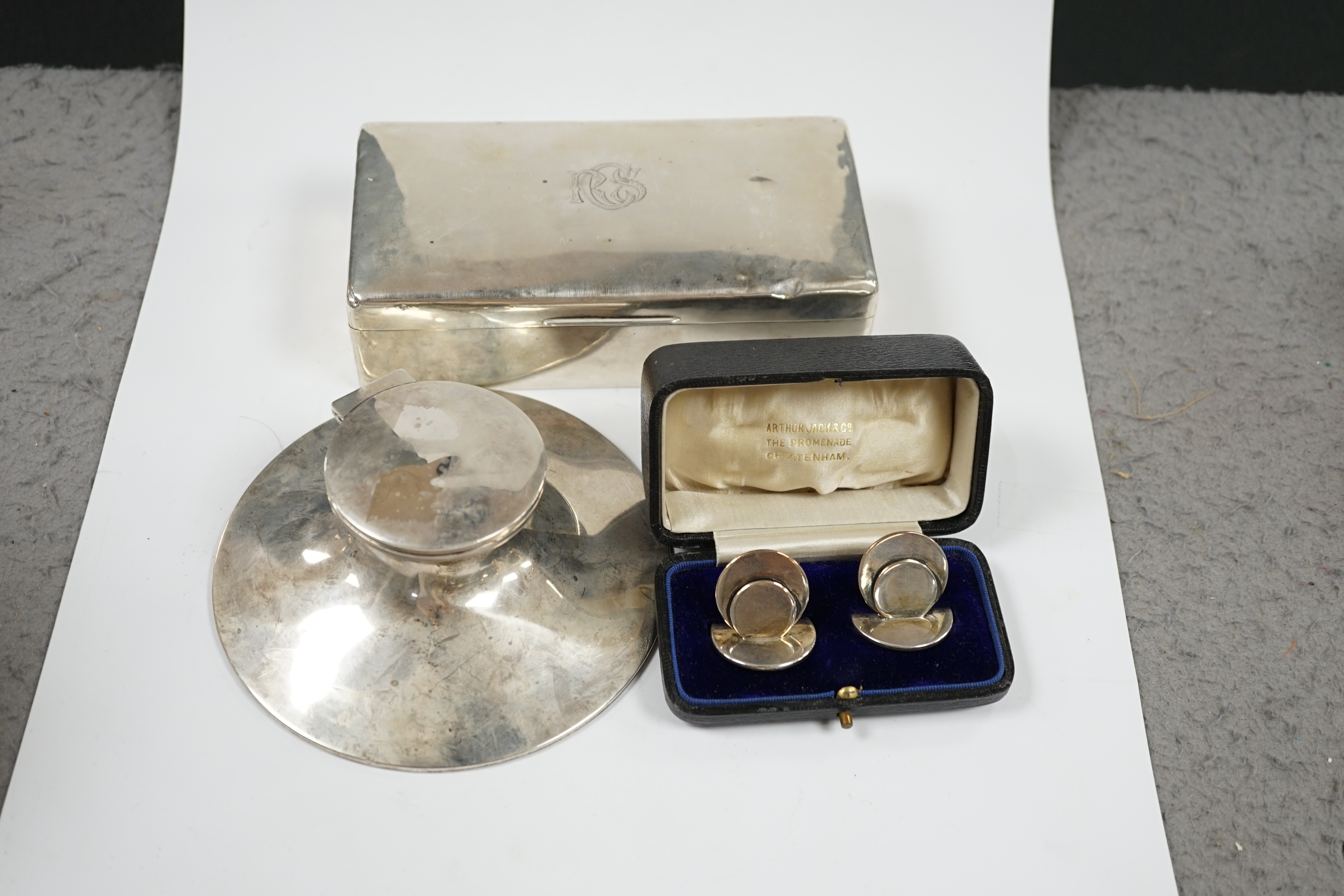 A silver mounted capstan inkwell, Birmingham, 1914, a silver mounted cigarette box and a cased pair of silver menu holders. Condition - poor to fair